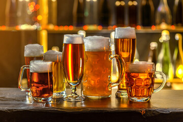 Glass of beer on the bar counter. Jugs, mugs, pints of brew beverage, ale, cider on the wooden...