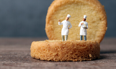Two pieces of cookies and two miniature chef. Miniature people and business concept.
