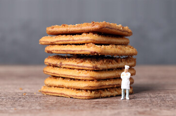A pile of crispy cookies and a miniature chef. Miniature people and business concept.
