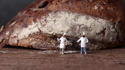 Obraz premium Roasted bread and two miniature chefs. Miniature people and business concept. 