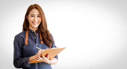 Charming young Asian businesswoman owner wearing an apron holding With clipboard front of an...