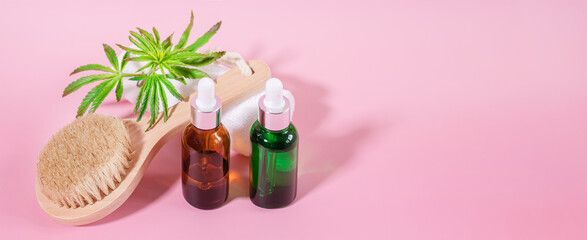 Black and green glass non-branded cosmetic oil and cannabis essential oil bottles and natural bristle wooden facial cleansing brush. Natural skin care and aromatherapy.Spa, wellness, massage concept