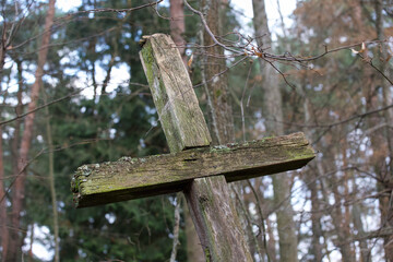 Old wooden cross on a background of trees.