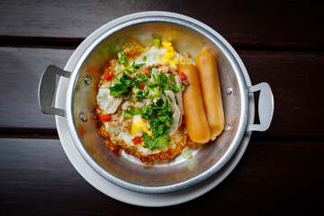 Scrambled eggs with hotdog, tomato and parsley. A rich breakfast of scrambled