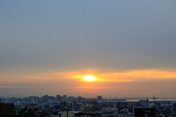 Fototapeta na wymiar 早朝、朝日にキラキラ輝き、黄金色に輝く海。兵庫県芦屋市芦屋浜より大阪湾を臨む。遠くに大阪南港のビルが見える