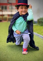 Niño saludando feliz y sonriente con capa negra