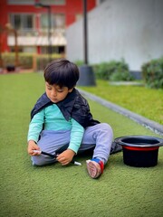 Niño mago pensativo con barita en mano en el parque de su casa