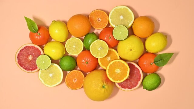 Fresh ripe citrus fruits filling pastel orange background. Stop motion flat lay
