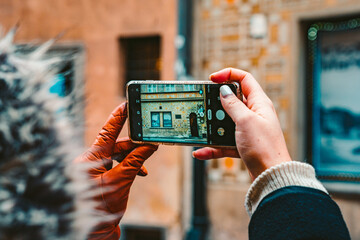 Gloved Woman Takes Picture of Historical Building on her Cell Phone