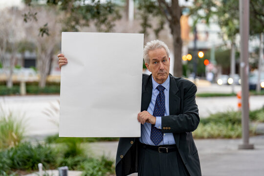 Businessman holding up a blank white paper sign