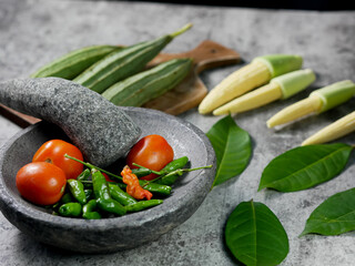 chilies and tomatoes in a mortar, recipe for vegetable baby corn and luffa acutangula with tomato sauce.