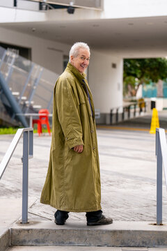 Old man posing in a green oversize trenchcoat