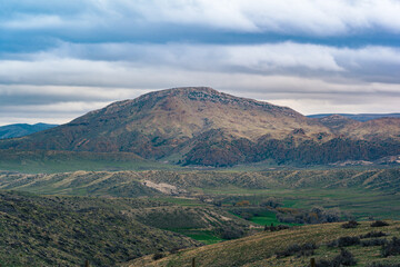 Fototapeta premium landscape of mountain range on top of green hillside with cloudy sky in Wyoming