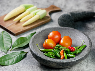 cayenne pepper and tomatoes in a stone mortar. tomato sauce recipe. food cooking concept