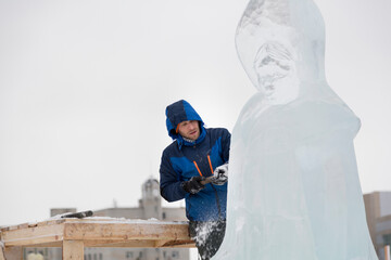 Portrait of a sculptor in a blue winter suit with a chisel in his hands on the scaffolding