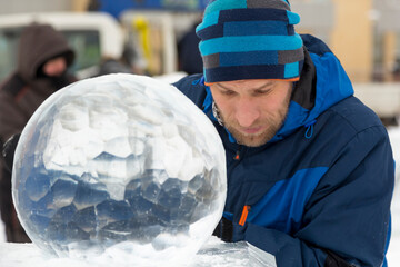 Portrait of a sculptor in a blue winter suit with a chisel in his hands at work