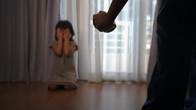 Agressive father holding alcohol yelling at his scared little daughter sitting and crying on floor, Abuse in family concept.