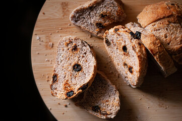 Slices of bread with raisins on a wooden cutting board close up top view, food photography