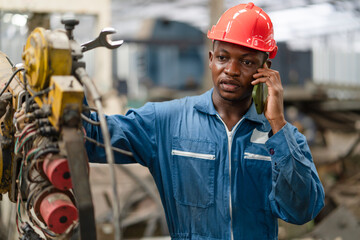African American engineer holding wrench tool and using smartphone while working in manufacturing...