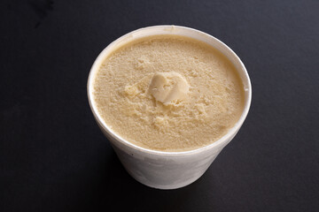 Bote de helado de vainilla, fondo negro. 