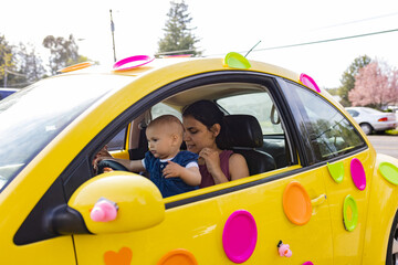 Happy mother and her adorable baby in colorful slug bug decorated for easter