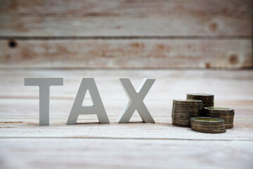 TAX alphabet letters with coins on wooden background