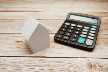 Model House and calculator on wooden background, realestate concept