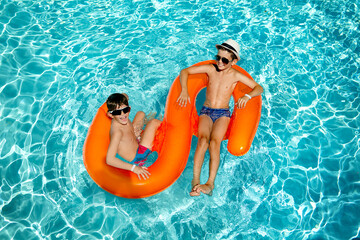 child in the pool. the boys in the pool are swimming on the orange circle.