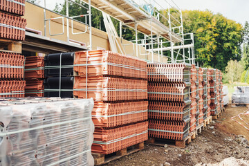 Long receding row of red roof tiles stacked on pallets