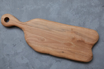 empty wooden cutting board lies on a gray background. Template for food photography.