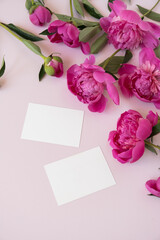 Blank paper invitation cards with copy space. Pink peony flowers bouquet on neutral pastel elegant pink background. Flat lay, top view minimal floral composition