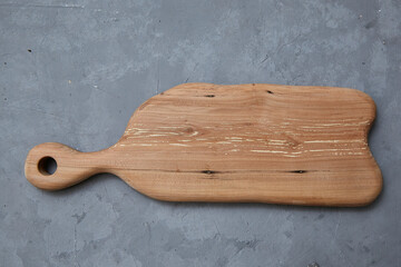 empty wooden cutting board lies on a gray background.