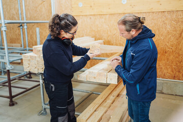 Two co-workers selecting a wooden beam in a workshop