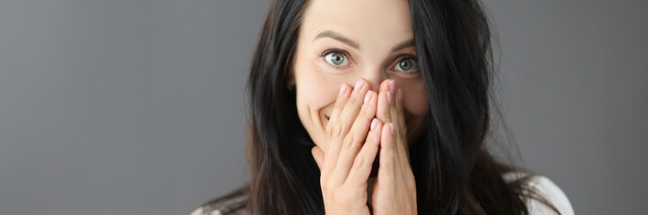 Portrait of smiling young woman covering nose with hand - obrazy, fototapety, plakaty