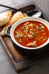 Chorba frik is a crushed green wheat and meat soup consumed in Algeria, particularly during the month of ramadan close-up in a plate on the table. Vertical