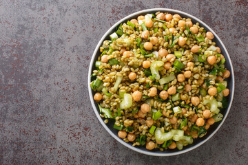 Close-up of a freekeh diet salad with chickpeas, celery and herbs in a plate on the table. horizontal top view from above