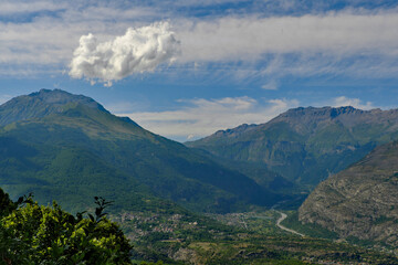 Fototapeta premium Dalla Madonna della Losa in Val di Susa una vista spettacolare sul fiume Dora e sui paesini di Giaglione e Venaus con nuvole bizzarre sulle Alpi Cozie