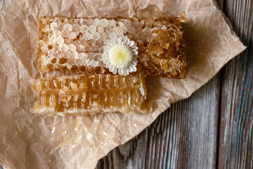 Sealed honeycomb of honey on parchment paper on wooden table