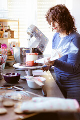 Caucasian woman carefully preparing a cake. Pastry at home. Selective focus.