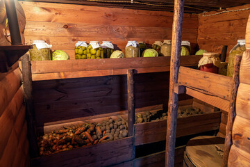 Preservation of vegetables in a warm cellar for winter period. Glass jars with pickled cucumbers on the shelf.