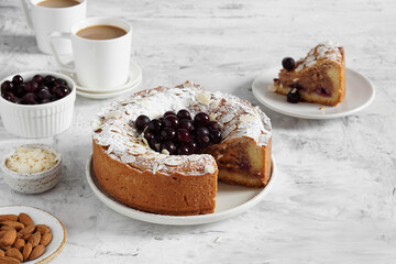 frangipane pie with frozen berries served on a table with a cup of coffee