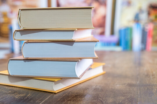 Stack of books on desk with blurred soft library background