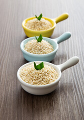 White sesame seeds in a little bowl on wooden table.