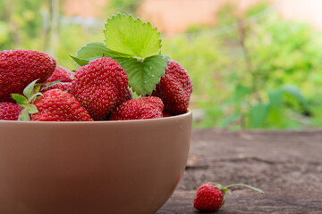 Red ripe juicy tasty strawberries in a bowl or ceramic plate on a wooden background. The concept of vegetarian, vegan and raw food and diet.