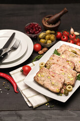 Sliced Traditional French terrine covered with bacon on dark wooden background