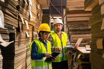 Engineer  wearing safety helmet and vest holding clipboard and take note on the paper in the...