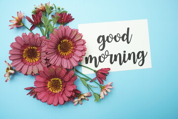 Good Morning typography text with daisy flowers on blue background