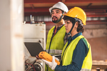 Engineer asian man and woman wearing safety helmet and vest holding clipboard and take note on the paper in the automotive part warehouse.Products and corrugated cardboard. 