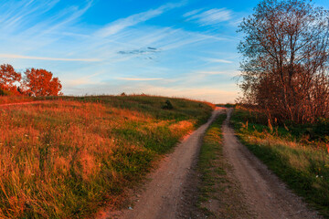 An orange sandy road at sunset with a walkway to the top with blue clouds.
