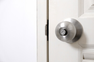 Stainless steel door knob or the handle on the wooden door In a brightly lit room. concept of cleanliness and hygiene.